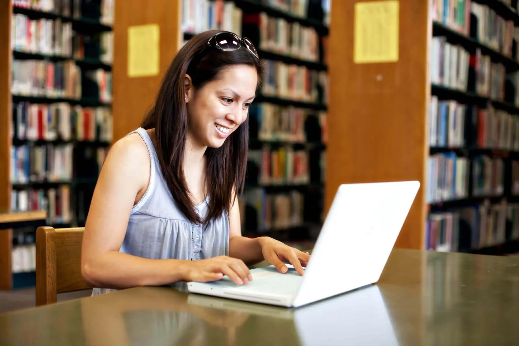 Blog 17 Woman smiling while using a laptop in a library