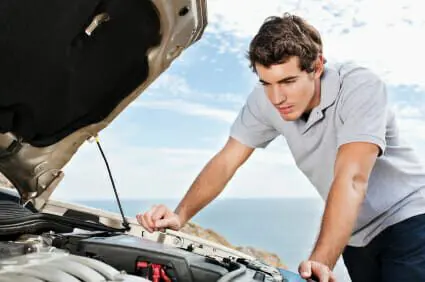 Blog 3 Young man looks under the hood of his car for engine trouble.