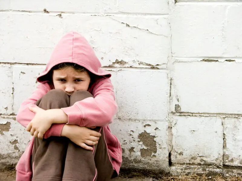 Child Abuse Prevention: Emotional Abuse Defined 1 Sad girl in pink sweater sitting against a wall