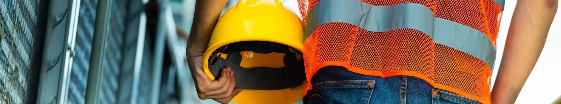 Blog 2 Construction worker with orange reflective safety vest holding yellow helmet