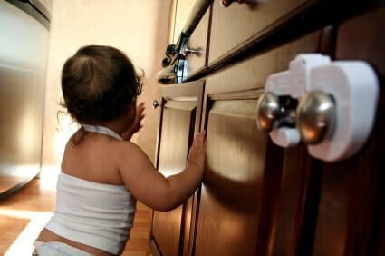 Blog 7 Baby resting on childproofed wooden kitchen cabinets