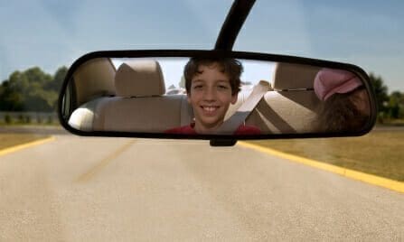 Blog 17 Child looking and smiling into rearview mirror