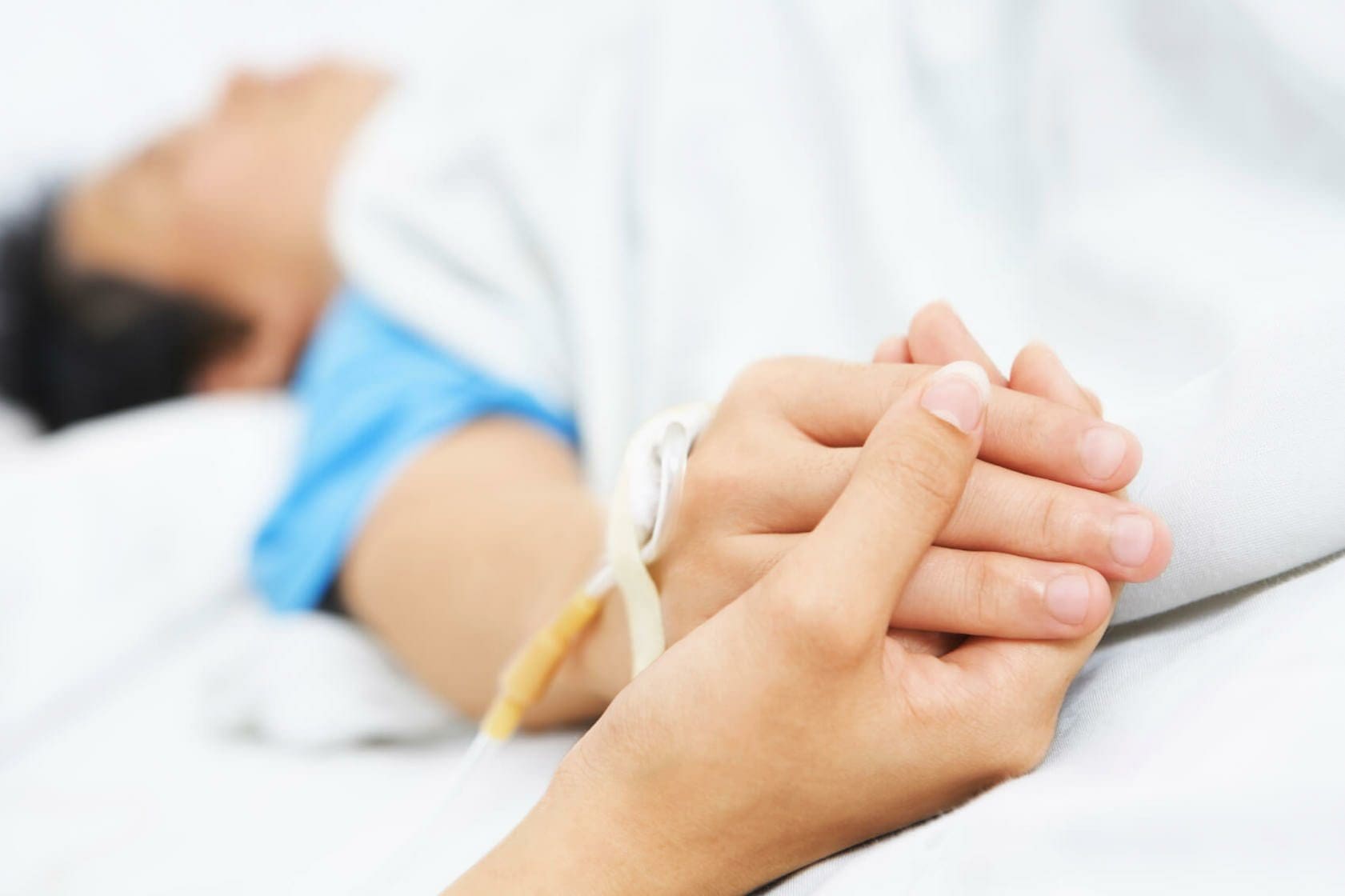 Blog 8 Person holding the hand of an injured patient lying in a hospital bed