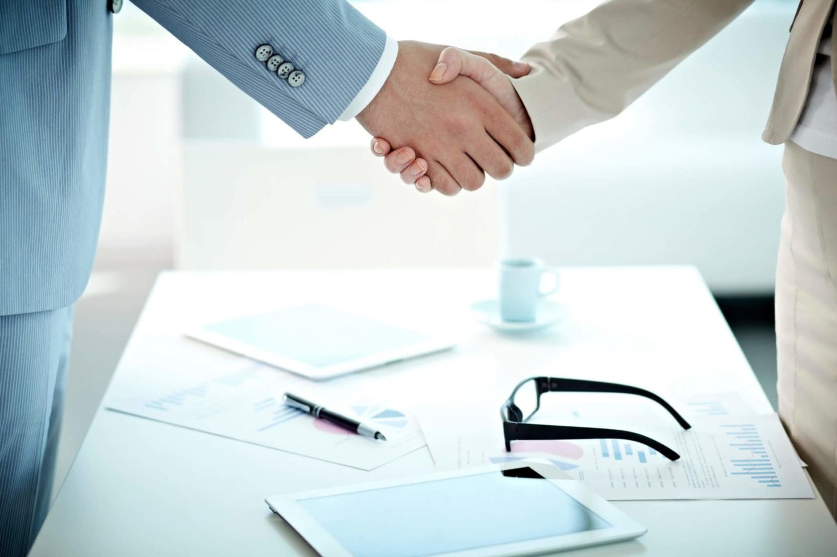 Blog 3 Person shaking hands with another person at a desk.
